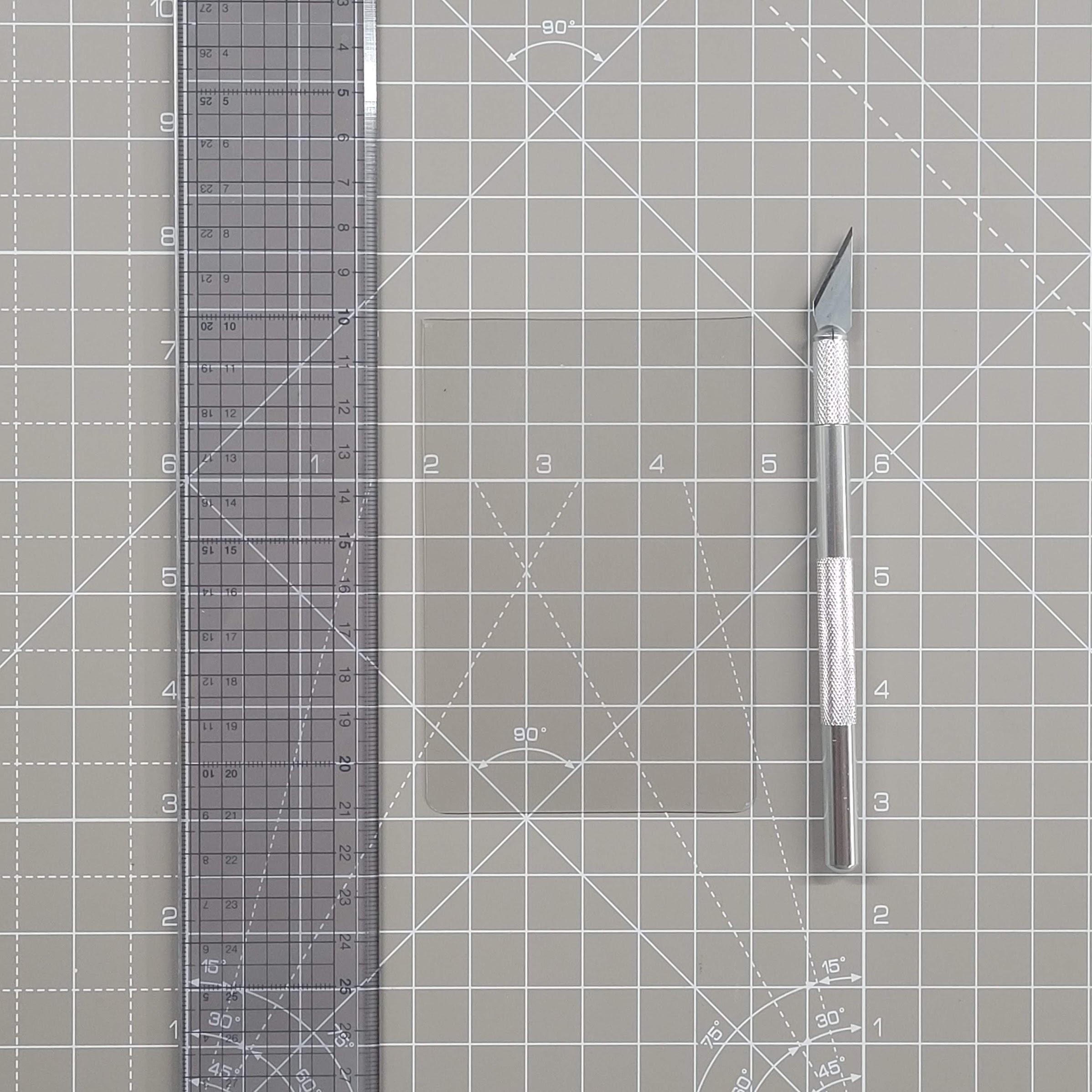 A transparent ruler, a plastic rectangle and a hobby knife